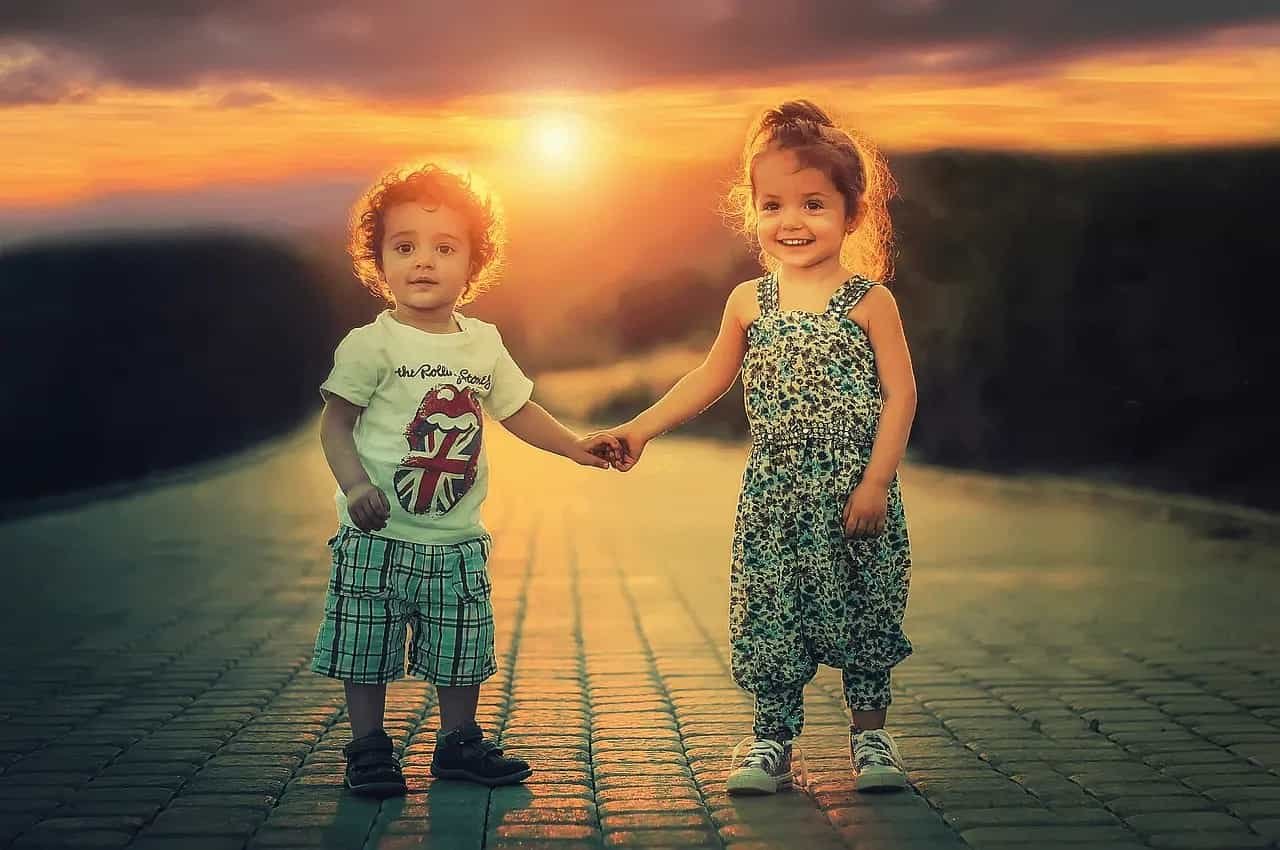 Duas crianças de mãos dadas ao pôr do sol, simbolizando união e crescimento juntos.