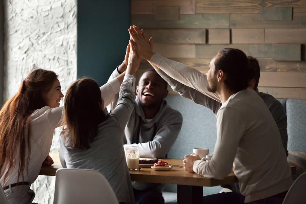 Equipe celebrando juntos em um ambiente casual, simbolizando os ‘Benefícios de Alcançar Sonhos’ e a ‘Celebração da Realização’, destacando a importância da ‘Motivação e Resiliência’ conjunta para ‘Concretizar’ objetivos.