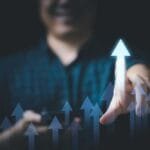 Nas mãos do empresário, a seta crescente brilhante simboliza o crescimento e o lucro nos negócios. Com visão estratégica e determinação, ele guia seu empreendimento rumo ao sucesso, transformando investimentos em oportunidades de crescimento. Cada passo é um impulso em direção ao ápice do progresso e da prosperidade. Imagem motivacional de uma mão interagindo com setas ascendentes, representando desenvolvimento pessoal e autoconhecimento para o artigo ‘Desperte o Gigante Adormecido: Realize Seus Sonhos’ na categoria ‘PRA VOCÊ CONCRETIZAR’ sob ‘Desenvolvimento Pessoal e Autoconhecimento’.