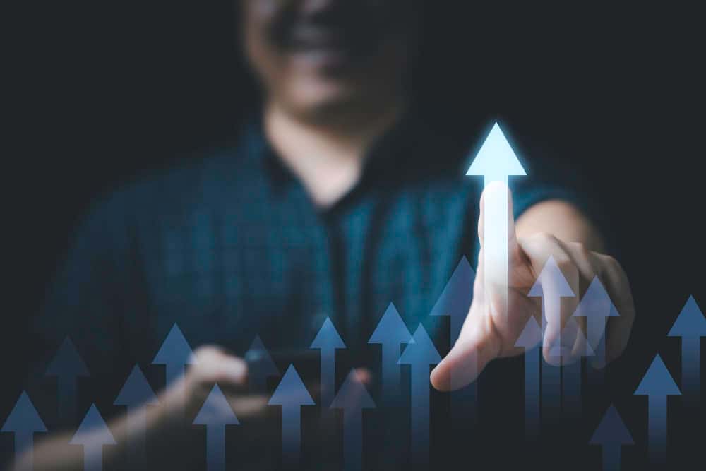 Nas mãos do empresário, a seta crescente brilhante simboliza o crescimento e o lucro nos negócios. Com visão estratégica e determinação, ele guia seu empreendimento rumo ao sucesso, transformando investimentos em oportunidades de crescimento. Cada passo é um impulso em direção ao ápice do progresso e da prosperidade. Imagem motivacional de uma mão interagindo com setas ascendentes, representando desenvolvimento pessoal e autoconhecimento para o artigo ‘Desperte o Gigante Adormecido: Realize Seus Sonhos’ na categoria ‘PRA VOCÊ CONCRETIZAR’ sob ‘Desenvolvimento Pessoal e Autoconhecimento’.