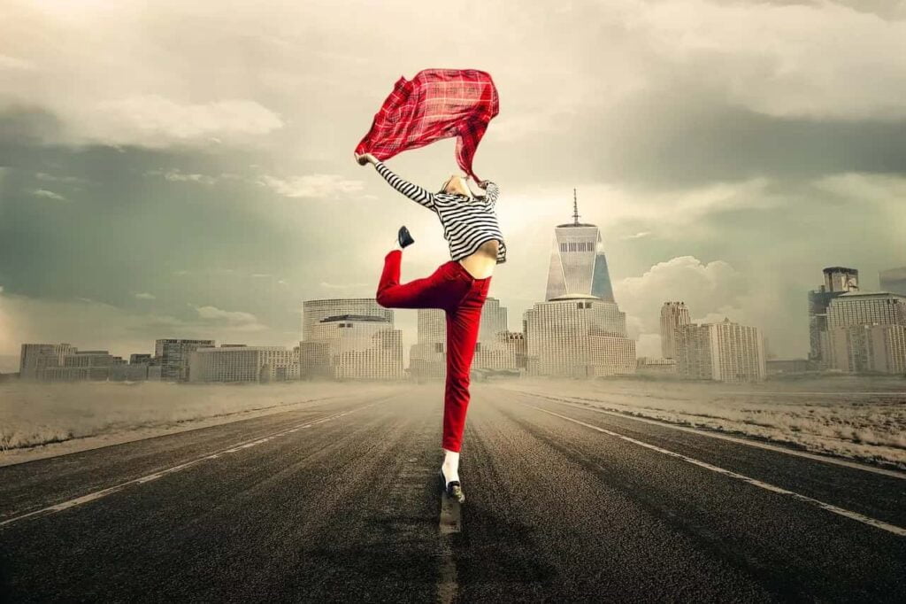 Esta imagem captura a jornada da liberdade e do crescimento pessoal. Uma estrada se estende até uma cidade distante, enquanto uma pessoa segura um tecido vermelho, simbolizando leveza e liberdade. O cenário inspira a autodescoberta e a busca por objetivos. Com estratégias práticas, alcançamos a liberdade almejada em nossas vidas, transformando sonhos em realidade.