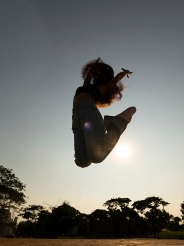 Silhueta de pessoa saltando contra pôr do sol radiante, representando ‘Motivação Interior’ e o potencial ilimitado dentro de cada um para ‘Concretizar’ sonhos com ‘Resiliência’.