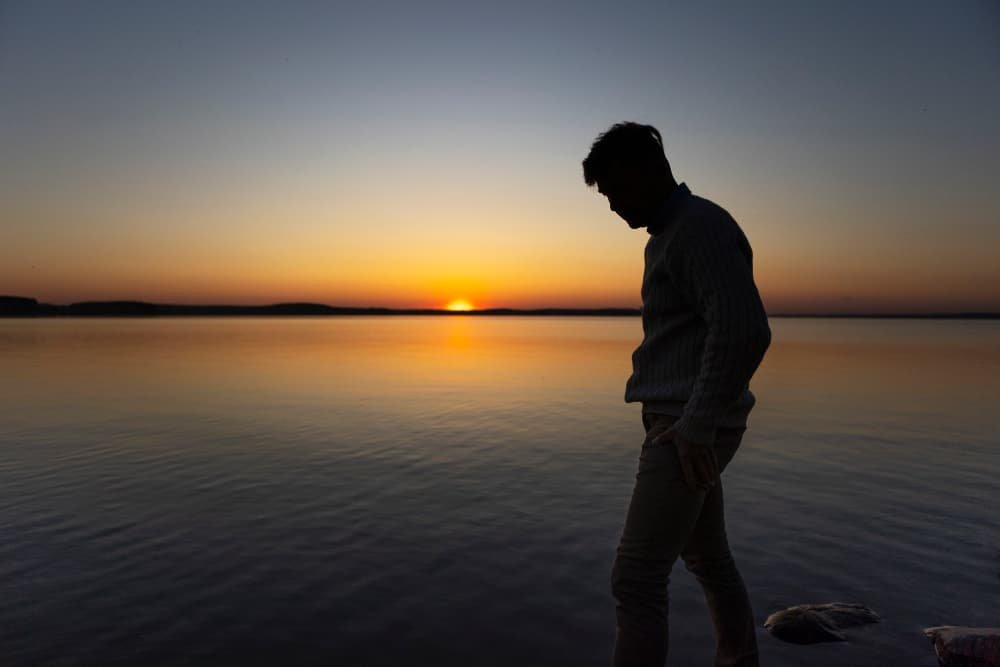 Silhueta contemplativa diante do pôr do sol - Refletindo sobre a essência da vida para motivação e resiliência.