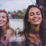 Duas pessoas refletindo e descontraídas à beira de um lago sereno, representando a fé como ferramenta de decisão em um artigo sobre motivação e resiliência na categoria ‘PRA VOCÊ CONCRETIZAR’.