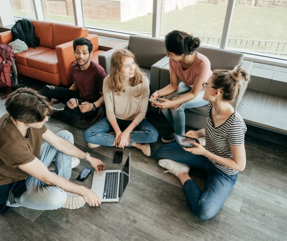 Grupo de pessoas trabalhando juntas em um espaço descontraído, utilizando laptops e tablets, representando colaboração, conexão e entusiasmo no ambiente profissional. Imagem do artigo "Trabalho Motivado: O Início", da categoria "Trabalho Motivado". Ideal para conteúdos sobre trabalho em equipe, motivação e estratégias para resultados extraordinários.