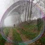 Caminhante seguindo por uma trilha montanhosa envolta por neblina, simbolizando perseverança, coragem e continuidade.