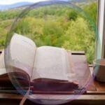 Livro aberto sobre uma mesa iluminada pela luz natural, simbolizando conhecimento, aprendizado e transformação.