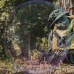Mochila apoiada ao lado de uma trilha em meio à natureza, simbolizando escolhas, leveza e preparação para a caminhada.