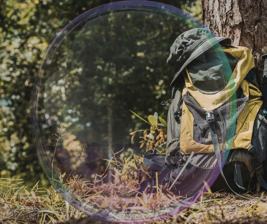 Mochila apoiada ao lado de uma trilha em meio à natureza, simbolizando escolhas, leveza e preparação para a caminhada.